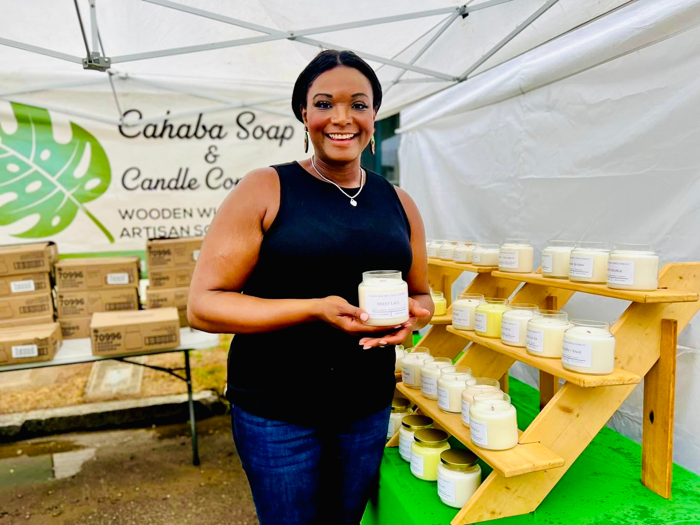 Janel, founder of Cahaba Luxury Goods, displaying handmade candles at an outdoor market
